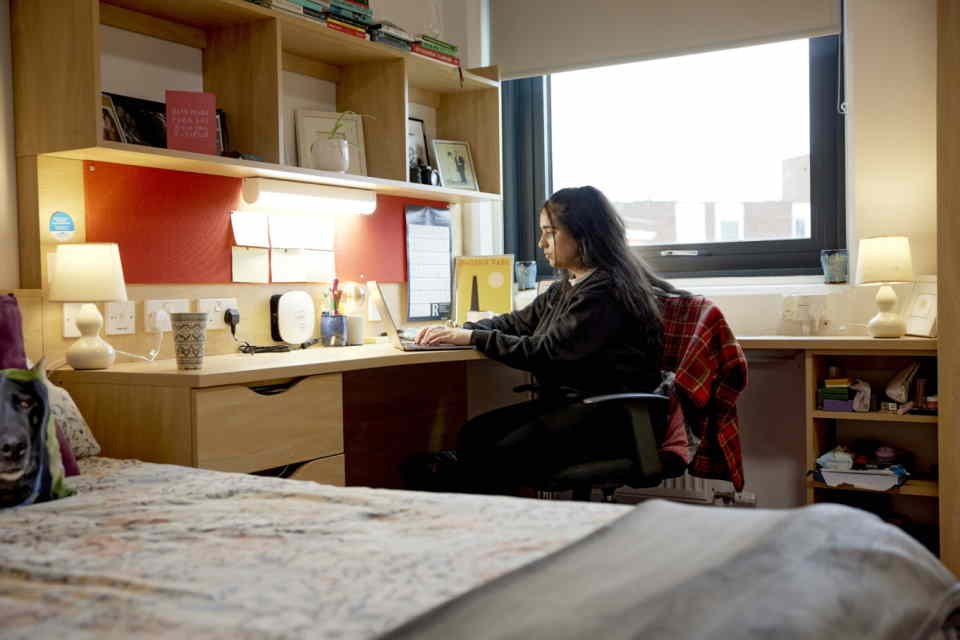 Student sat at their desk with a light on